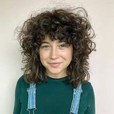 Person with voluminous curly shag mullet with bangs