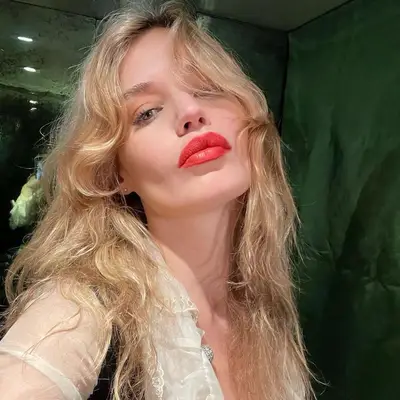 Georgia May Jagger with long, blonde curly hair with curtain bangs