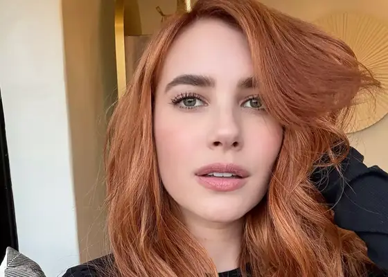 Emma Roberts taking a selfie holding her long copper red hair