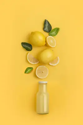Lemons and a juice bottle on a yellow background