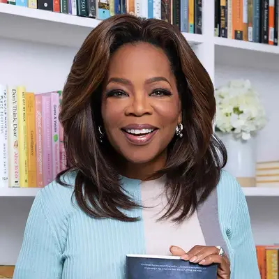 Oprah Winfrey holding a book in front of a bookshelf