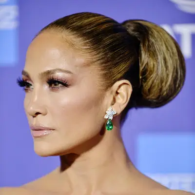 Jennifer Lopez wears a tucked-under, slicked back ponytail hairstyle