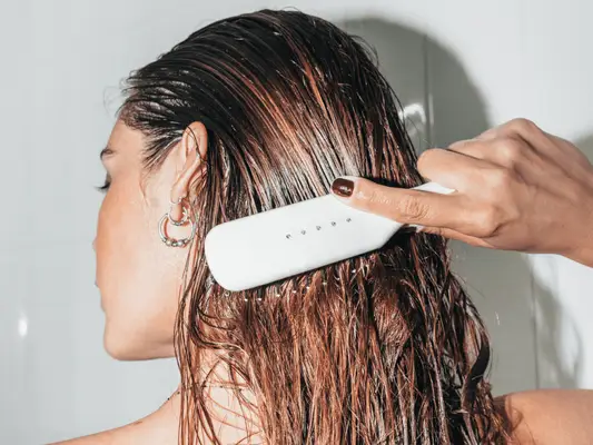 A woman brushing her wet hair in the shower