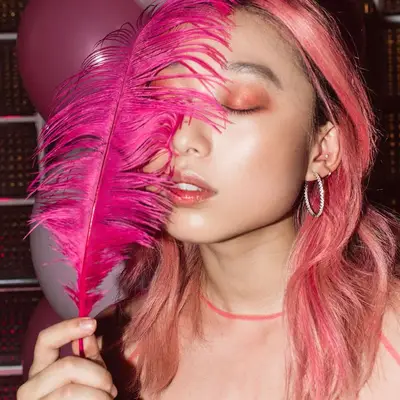 Margaret Zhang holding hot pink feather with vibrant Rose Gold Hair 