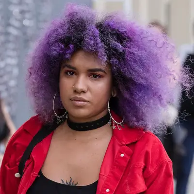 Woman wears purple, bob length natural curls
