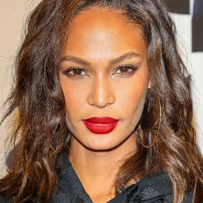 Joan Smalls wears a windswept wavy lob hairstyle and large hoop earrings