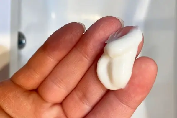 Closeup of hand with Drunk Elephant Silkamino Mega Moisturizing Masker cream 