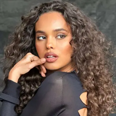 Alisha Boe with natural curly hair and a black dress