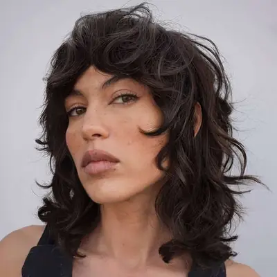 a woman with dark brown hair showing a curly shag haircut
