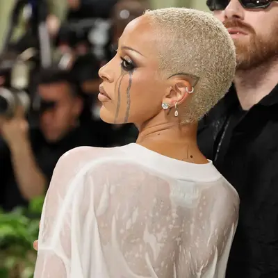 Doja Cat with blonde buzzed hair and a scalp/ear tattoo at the 2024 Met Gala in New York City