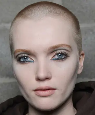 Ruth Bell with strawberry blonde buzz cut and dramatic eye makeup