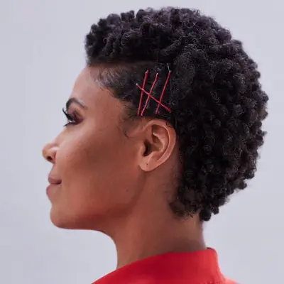 Sanaa Lathan with a short pixie afro hairstyle and red bobby pins on the side