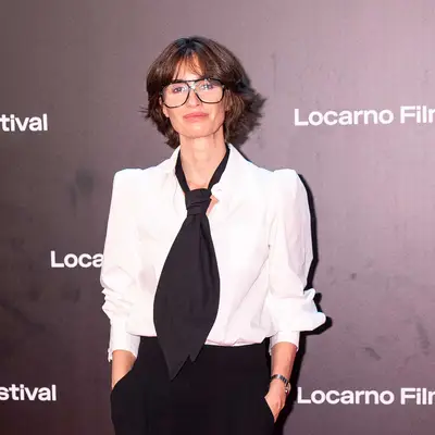 Paz Vega wearing large black frame glasses with bouncy bob with fringe