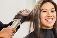 A person using the Shark FlexStyle Air Styling and Drying System on another person