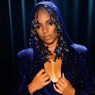 Alicia Keys in a blue jumpsuit, with beads added to her braids