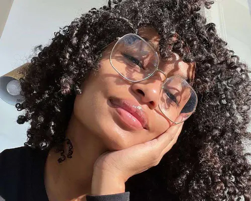 Yara Shahidi wears large wire glasses and her natural type 3C curly hair