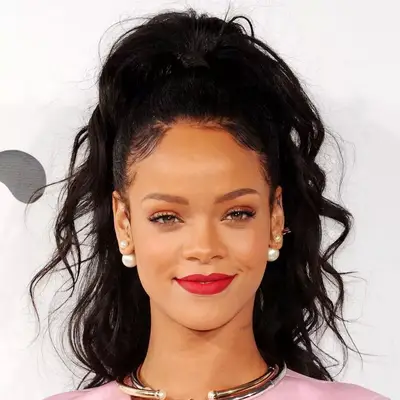 Rihanna wears her curly hair in a half-up, half-down ponytail hairstyle