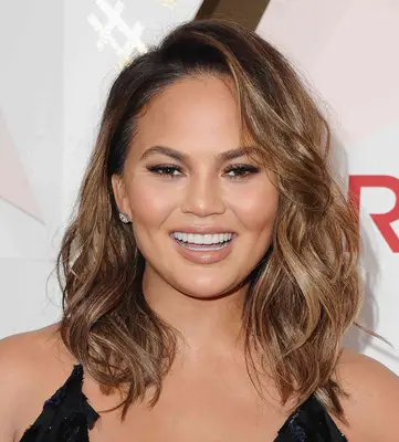 Chrissy Teigen with wavy brown and blonde hair at the 2017 Revolve Awards in Hollywood, California 
