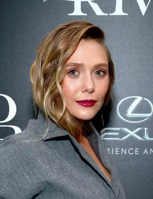 Elizabeth Olsen with a wavy faux lob hairstyle and gray jacket