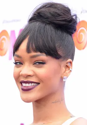 Rihanna with blunt and short bangs and a bun