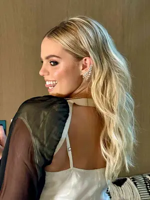 Back view of Renee Rapp with voluminous wavy hairstyle and statement earring