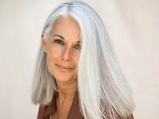 woman with light gray hair against neutral background