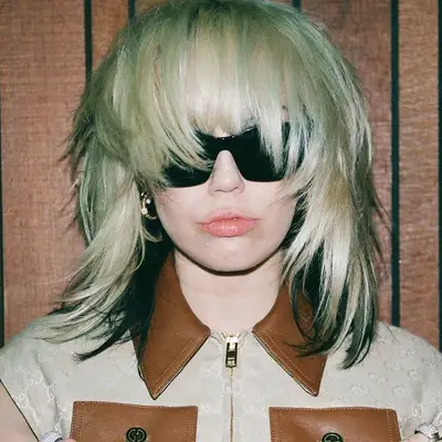 Miley Cyrus wears a platinum shag haircut with bangs and black underside