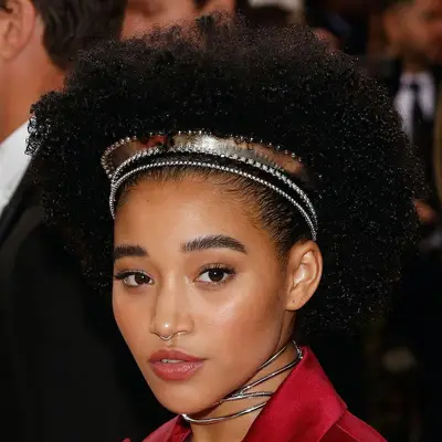 Amandla Stenberg wears a curly Afro hairstyle with golden and bedazzled headbands