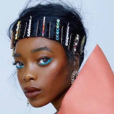 Woman with multicolored bedazzled bobby pins holding hair swept across forehead