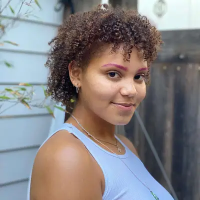 A person with a shaggy mullet and baby bangs