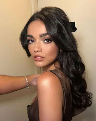 Singer-actor Rachel Zegler with a big hair bow in a half-up, half-down hairstyle