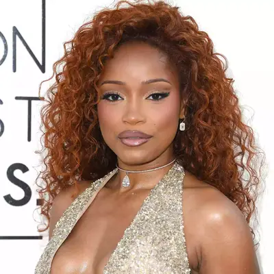 Keke Palmer wearing auburn curly hairstyle