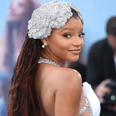 Halle Bailey wearing red locs and mermaid-inspired headpiece
