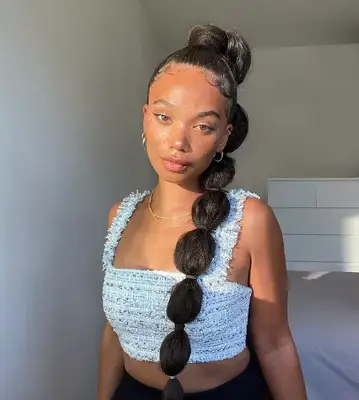 A woman wears a high ponytail with a bubble braid