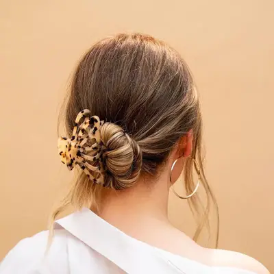 Back view of messy bun hairstyle with tortoiseshell claw clip and silver hoop earrings