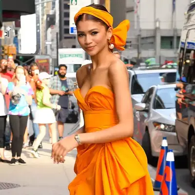 Zendaya with a bright orange headscarf and matching dress