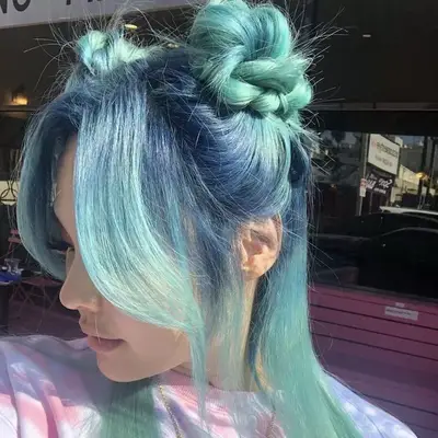 Woman with blue to green ombre hair with half-up space buns