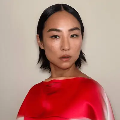 Greta Lee wears her layered bob is a slicked down center part style with flipped ends