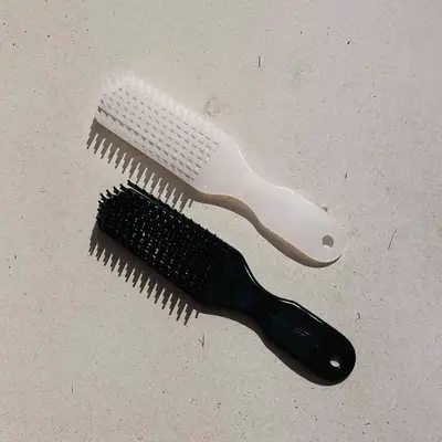 Woman wearing cornrows standing against a wall.