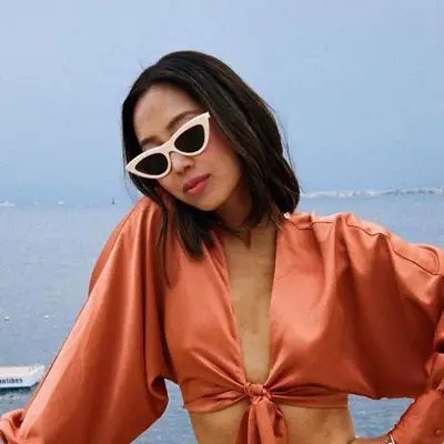 Aimee Song wears an A-line long bob haircut with cat eye sunglasses and a silk tie top