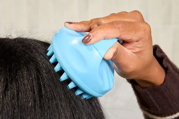 Vegamour GRO Revitalizing Scalp Massager on a shelf in a shower