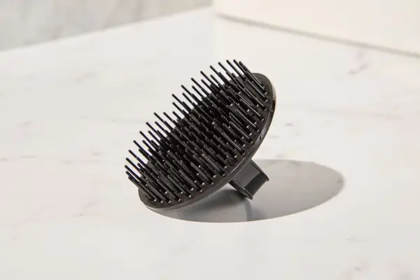The Denman Palm Styler for Detangling, Massaging & Styling on a counter
