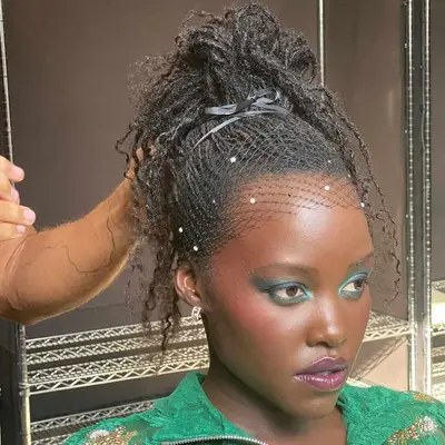 lupita nyongo wearing her locs in a loose updo ponytail