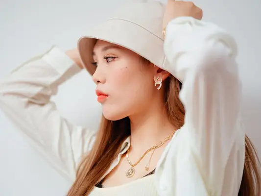 Woman wearing a bucket hat, hands on her head