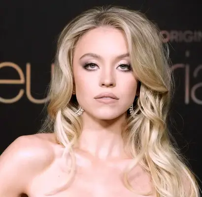 Sydney Sweeney attends a Euphoria premiere wearing highly glamorized hair and makeup, hoop earrings and a strapless dress. 