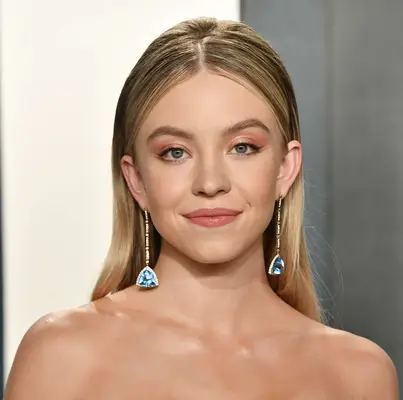 Sydney Sweeney attends a Vanity Fair party in a strapless dress and long earrings and full, straight highlighted hair