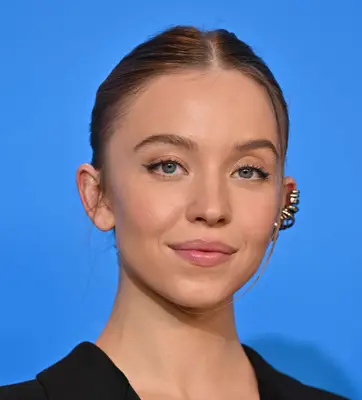 Sydney Sweeney wears her hair pulled back with a center part, soft makeup and one ear heavily lined with jewelry during a film festival