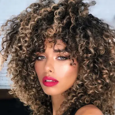 A woman with curly, dark cookies and cream blonde hair 
