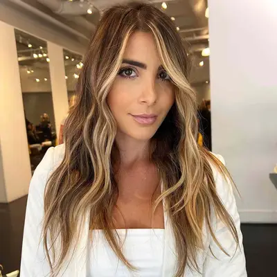 A woman with wavy face-framing blonde highlights
