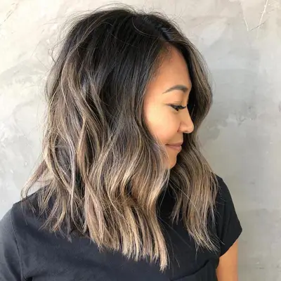 A woman with dark smoky blonde highlighted hair